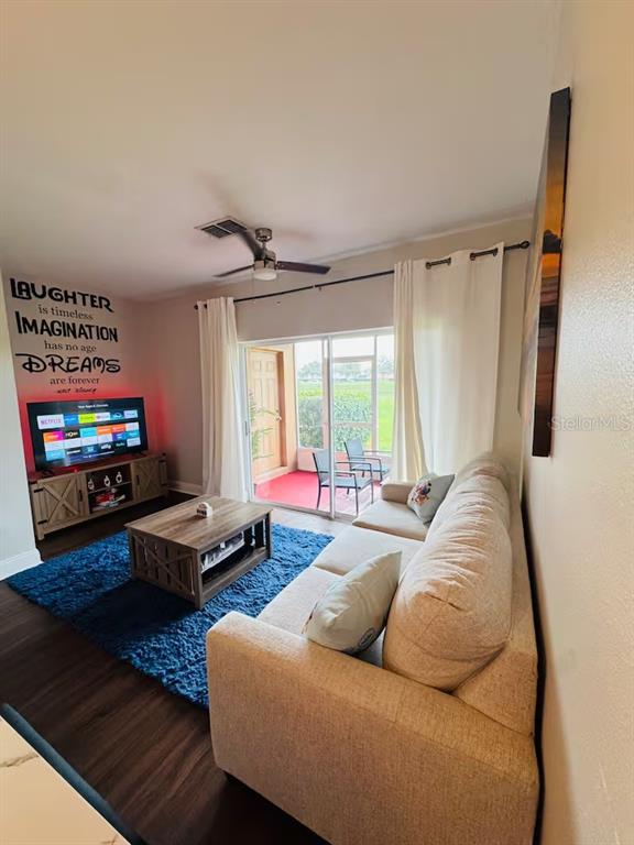 A living room features a beige sofa, blue rug, television, and sliding glass doors — 774 CHELSEA DRIVE, DAVENPORT, FL