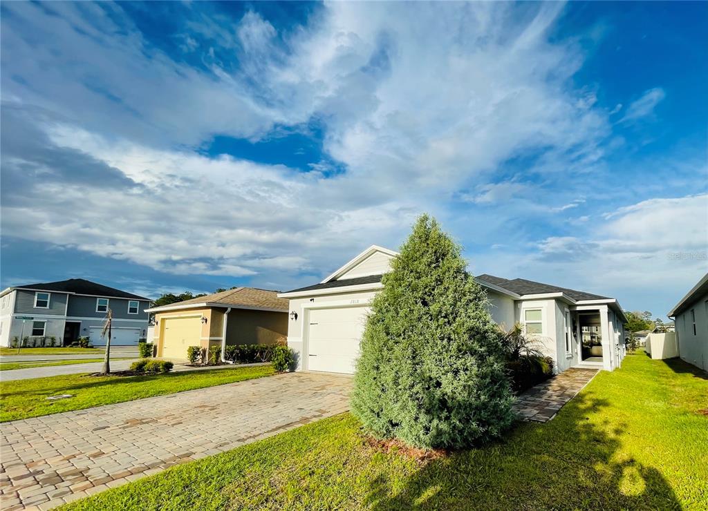 A single-story house with a white garage and a large evergreen tree in the yard — 2818 SANCTUARY DRIVE, CLERMONT, FL