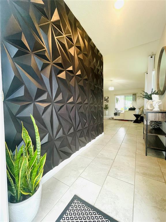 A hallway features a black geometric accent wall, light tile flooring, and a potted plant — 2818 SANCTUARY DRIVE, CLERMONT, FL