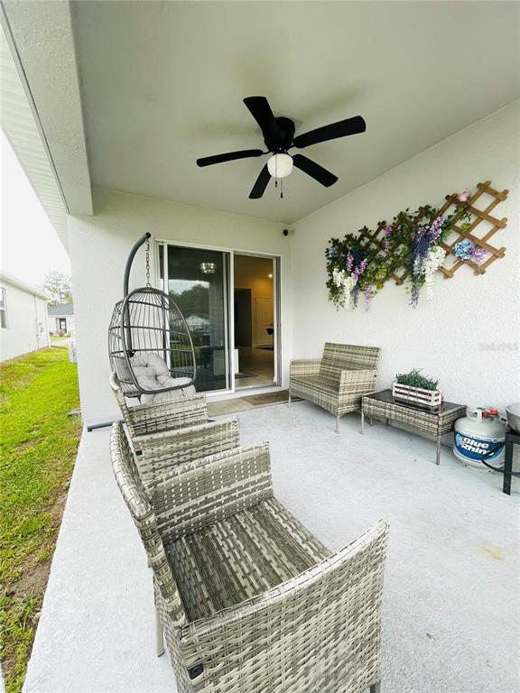 A covered patio features wicker furniture, a hanging chair, and a decorative floral wall trellis — 2818 SANCTUARY DRIVE, CLERMONT, FL