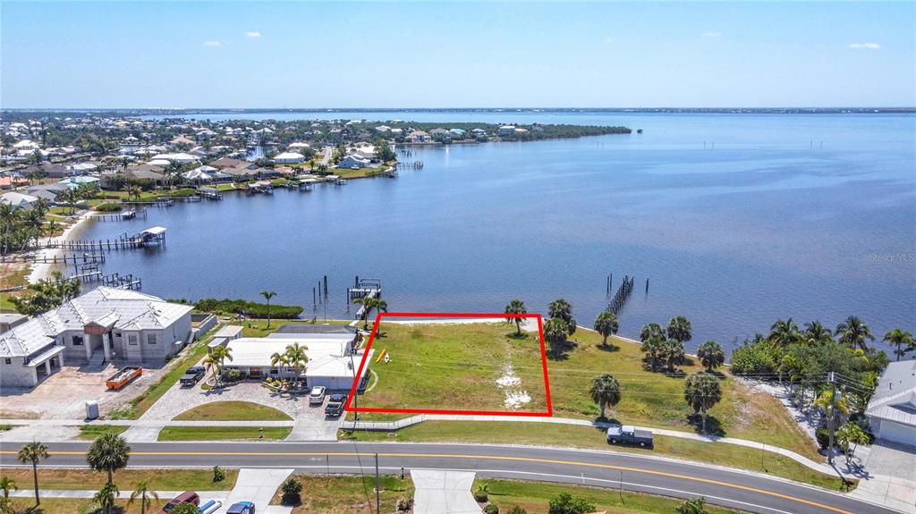 An aerial view shows a vacant waterfront lot outlined in red next to a house — 4456 HARBOR BOULEVARD, PORT CHARLOTTE, FL