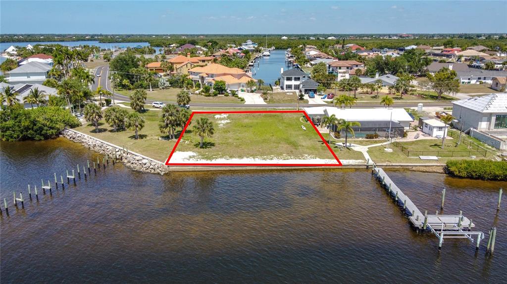 An aerial view shows a vacant waterfront lot outlined in red next to a house — 4456 HARBOR BOULEVARD, PORT CHARLOTTE, FL