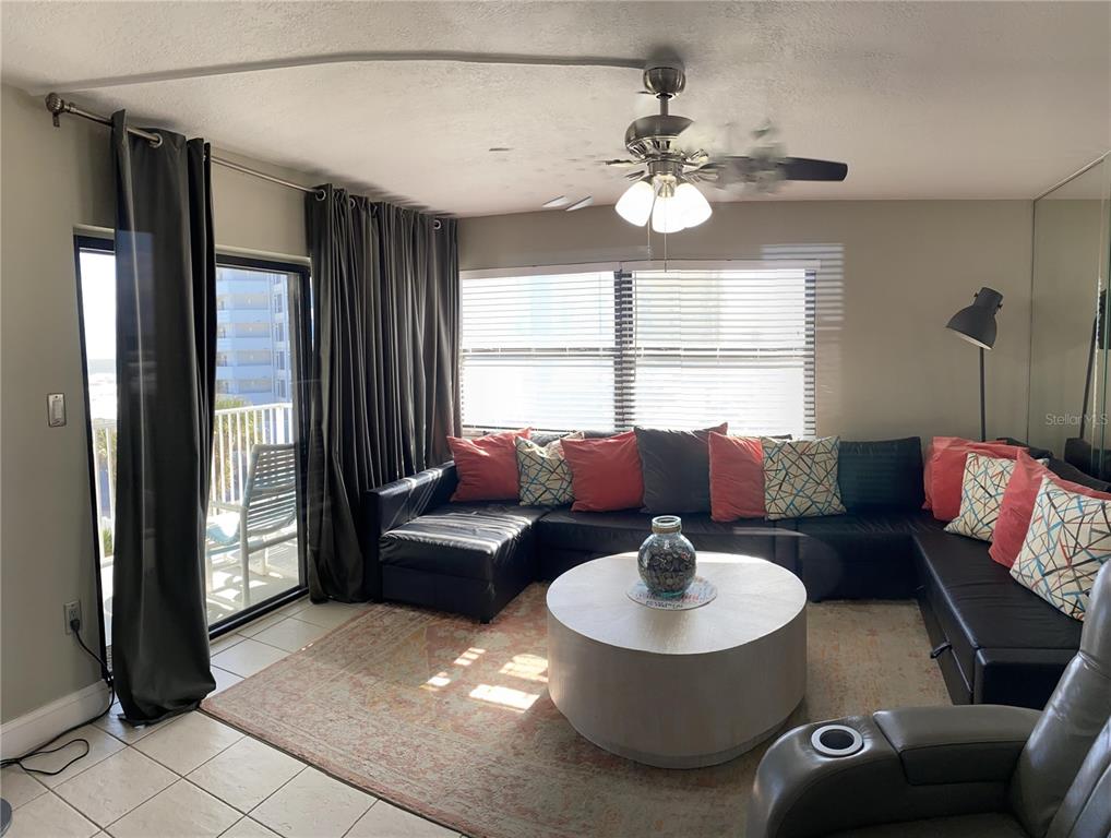 A living room features a black sectional sofa, a round coffee table, and sliding glass doors — 1571 S ATLANTIC AVENUE UNIT 403, NEW SMYRNA BEACH, FL