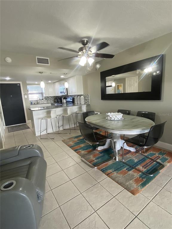 An open-concept dining area features a round table, modern chairs, and a kitchen island — 1571 S ATLANTIC AVENUE UNIT 403, NEW SMYRNA BEACH, FL
