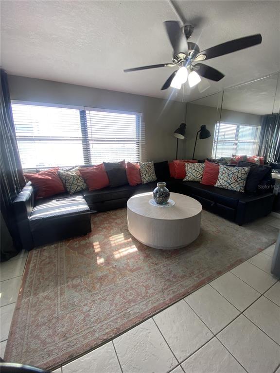 A living room features a large black sectional sofa, a round coffee table, and tiled floors — 1571 S ATLANTIC AVENUE UNIT 403, NEW SMYRNA BEACH, FL