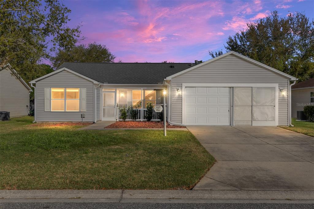 A single-story house with light gray siding, a white garage door, and a screened-in porch — 1449 MURRELLS INLET LOOP, THE VILLAGES, FL