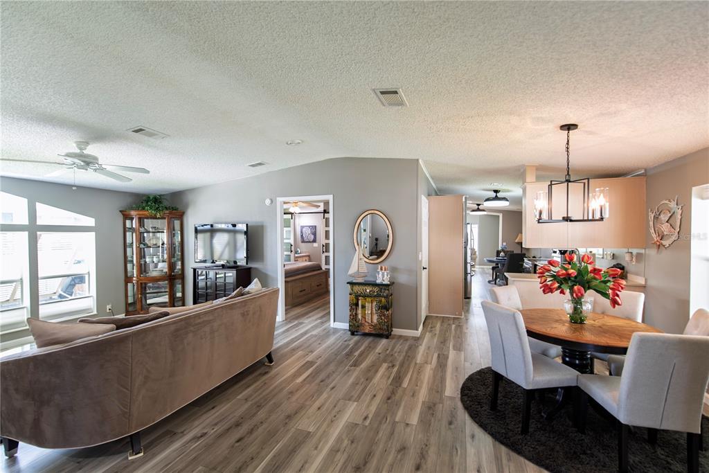 An open-concept living and dining area features wood-look flooring, gray walls, and a ceiling fan — 44 WINDMILL BOULEVARD, PUNTA GORDA, FL