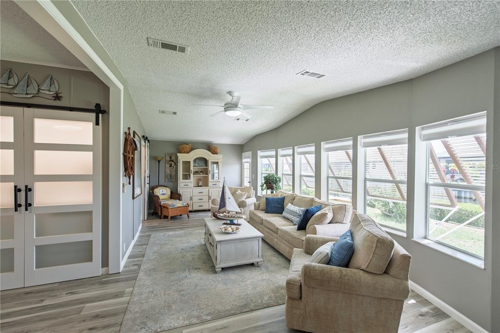 A living room features a beige sofa, armchairs, a coffee table, and large windows — 44 WINDMILL BOULEVARD, PUNTA GORDA, FL