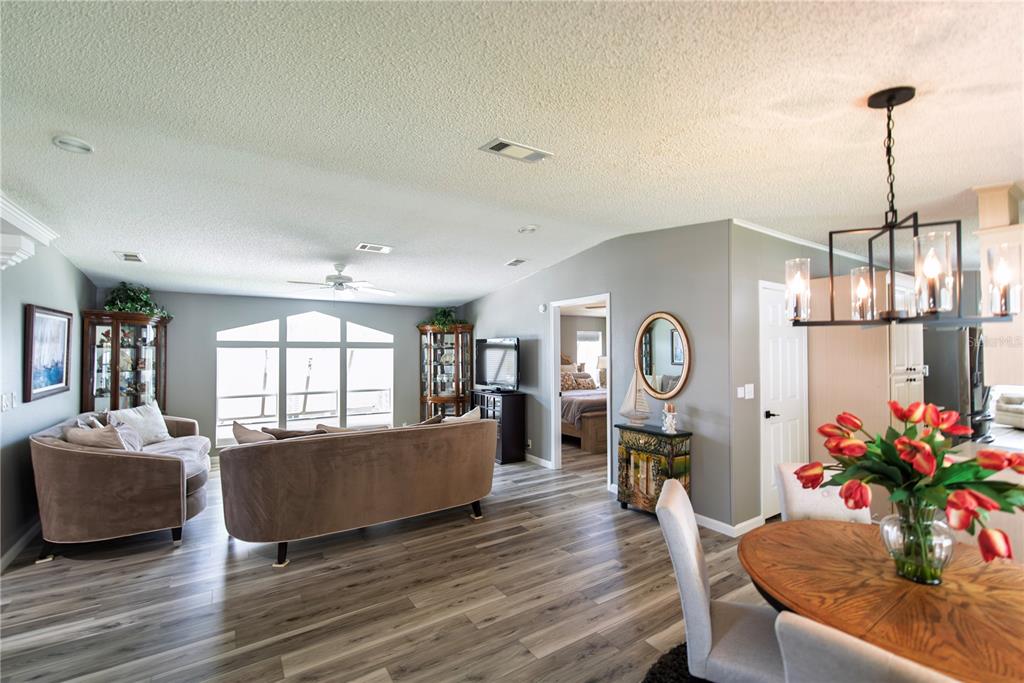 A living room with wood-look flooring, a large sofa, and a dining area with flowers — 44 WINDMILL BOULEVARD, PUNTA GORDA, FL