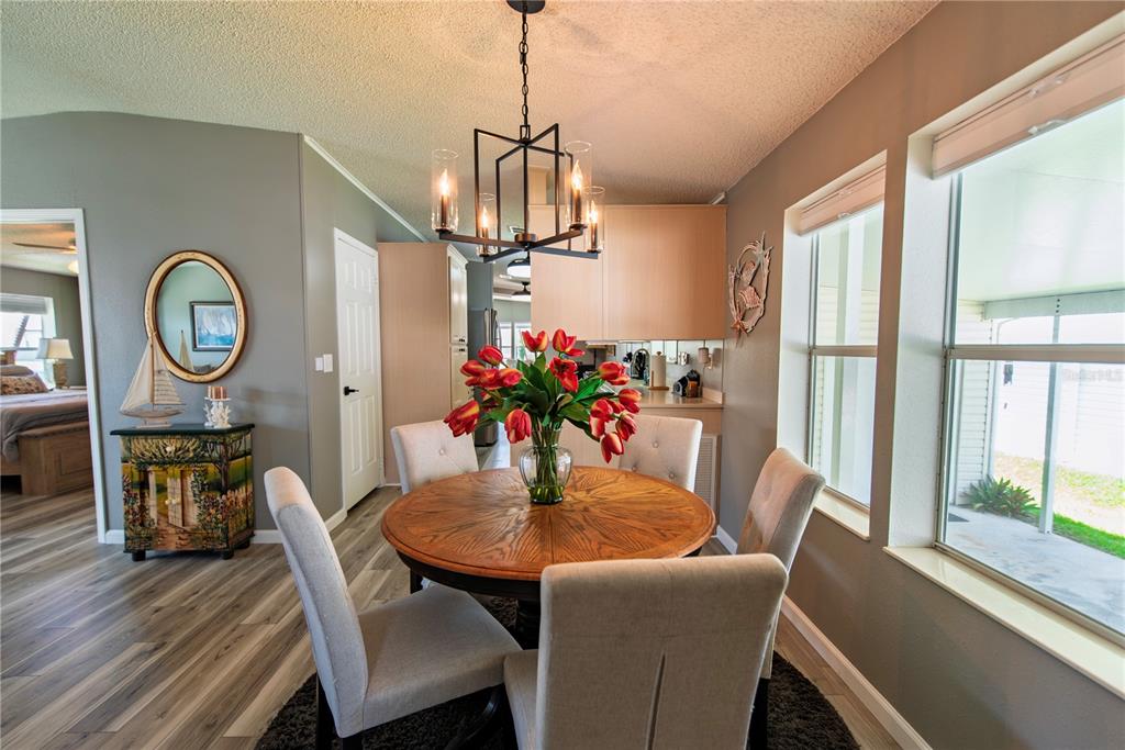 A dining area features a round wooden table, upholstered chairs, and a modern chandelier — 44 WINDMILL BOULEVARD, PUNTA GORDA, FL