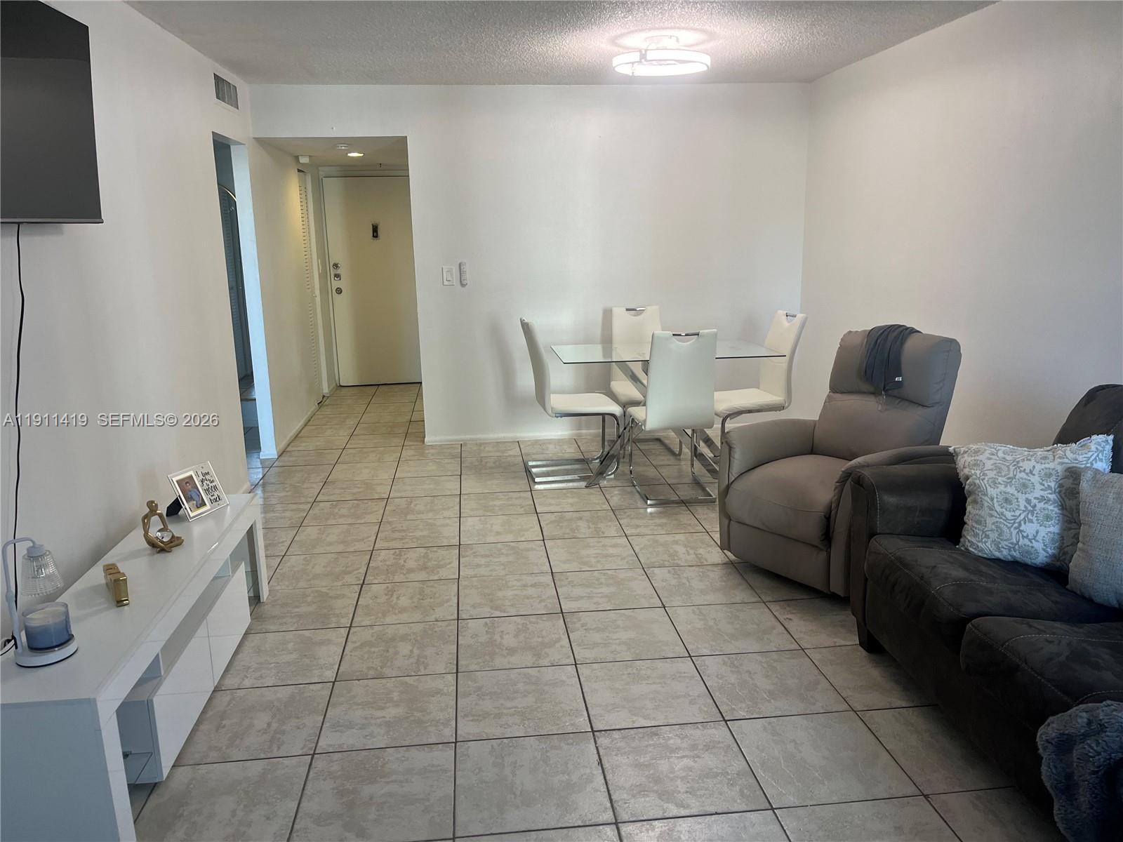 A living and dining area features white walls, tile flooring, and modern furniture — 1825 W 44th Pl # 309, Hialeah FL 33012, HIALEAH, FL