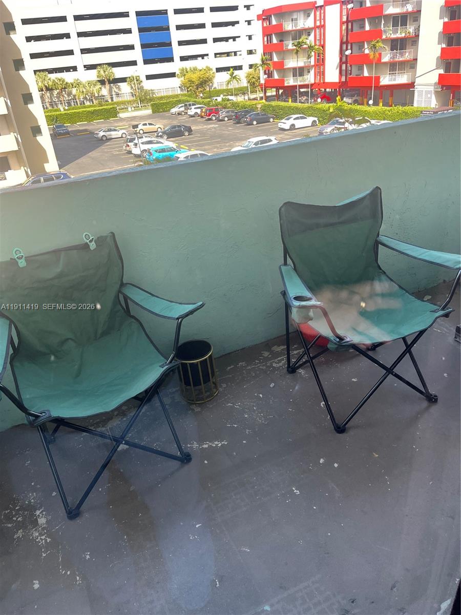 Two green folding chairs sit on a balcony overlooking a parking lot and buildings — 1825 W 44th Pl # 309, Hialeah FL 33012, HIALEAH, FL
