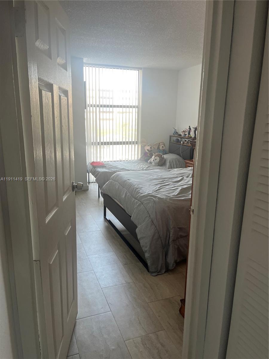 A bedroom with two beds, tile flooring, and a large window with vertical blinds — 1825 W 44th Pl # 309, Hialeah FL 33012, HIALEAH, FL