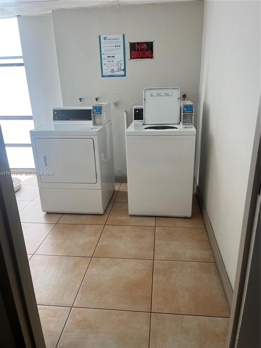 A laundry room features a white dryer and a top-loading washing machine on tiled floors — 1825 W 44th Pl # 309, Hialeah FL 33012, HIALEAH, FL