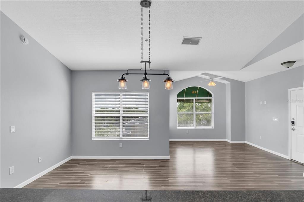 An open-concept living area features gray walls, wood-look flooring, and a kitchen with bar seating — 10764 70TH AVENUE UNIT 3307, SEMINOLE, FL