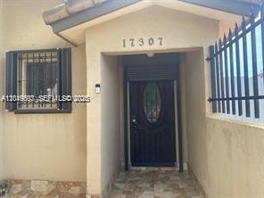 The exterior entrance features a dark wood door, a window with security bars, and a tiled porch — 17307 SW 115th Ave, Miami FL 33157, MIAMI, FL