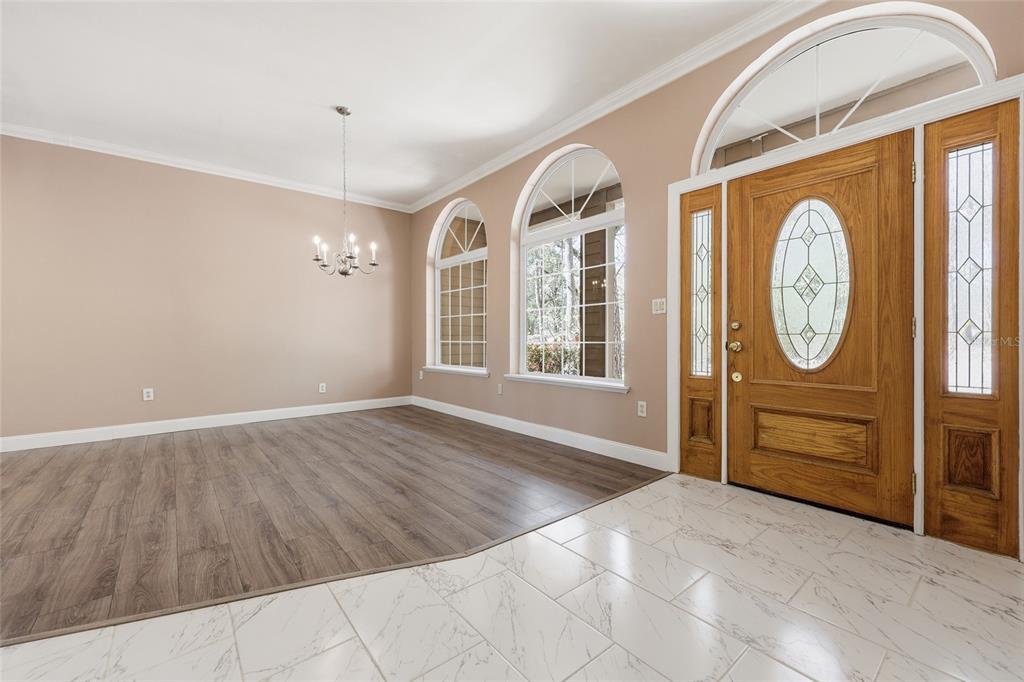 A foyer with white marble-look tile floors transitions into a dining room with wood flooring — 19513 NW 240TH LANE, HIGH SPRINGS, FL
