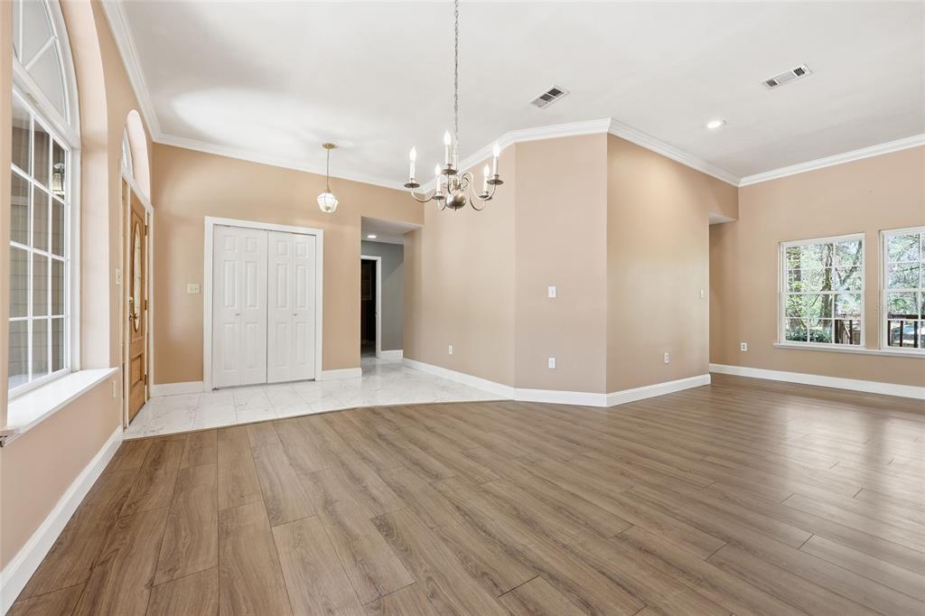 A spacious room with light wood-look flooring, beige walls, a chandelier, and a tiled entryway — 19513 NW 240TH LANE, HIGH SPRINGS, FL