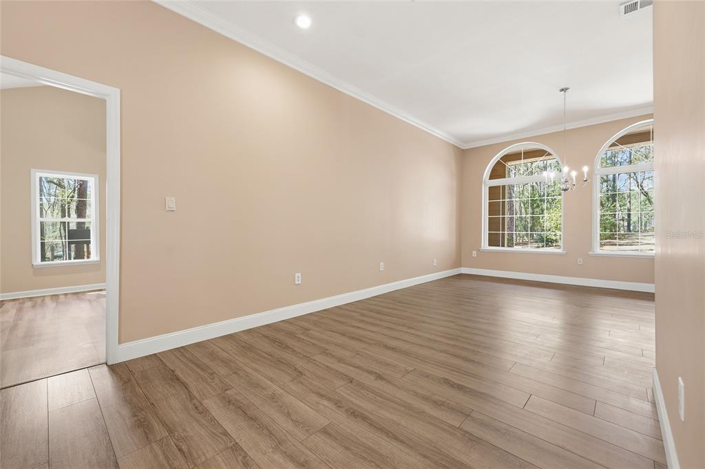 An empty dining room with light-colored walls, wood-look flooring, and two large arched windows — 19513 NW 240TH LANE, HIGH SPRINGS, FL