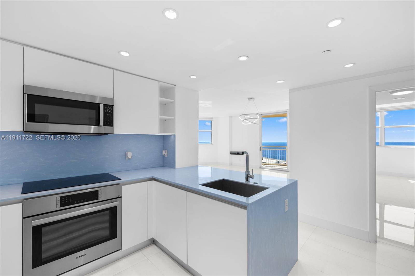 A bright, empty room features white tile floors, a large window, and a balcony overlooking the ocean — 2475 Brickell Ave # 1907, Miami FL 33129, MIAMI, FL