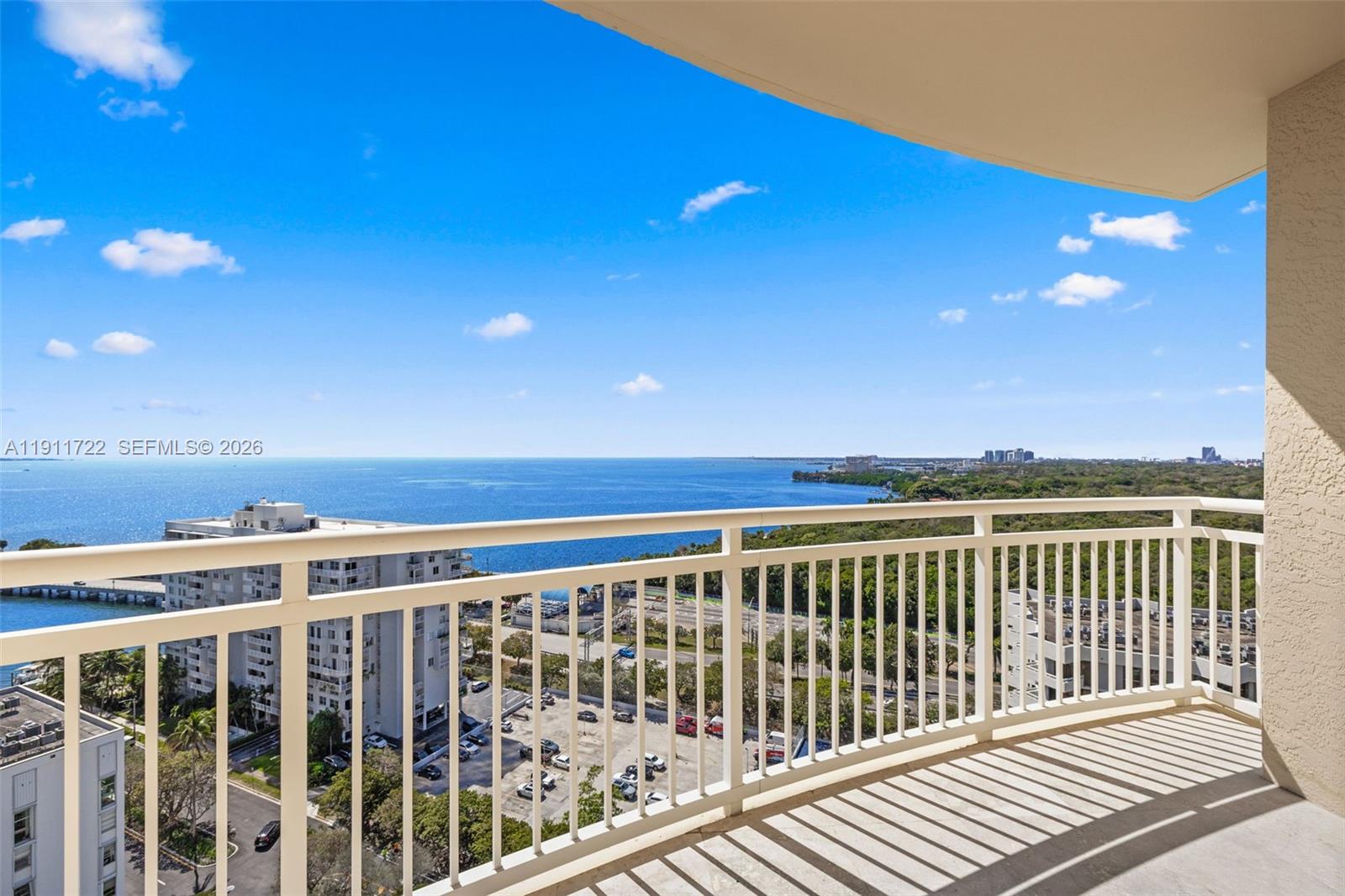 An aerial view shows a tall residential building surrounded by parking lots, tennis courts, and greenery — 2475 Brickell Ave # 1907, Miami FL 33129, MIAMI, FL