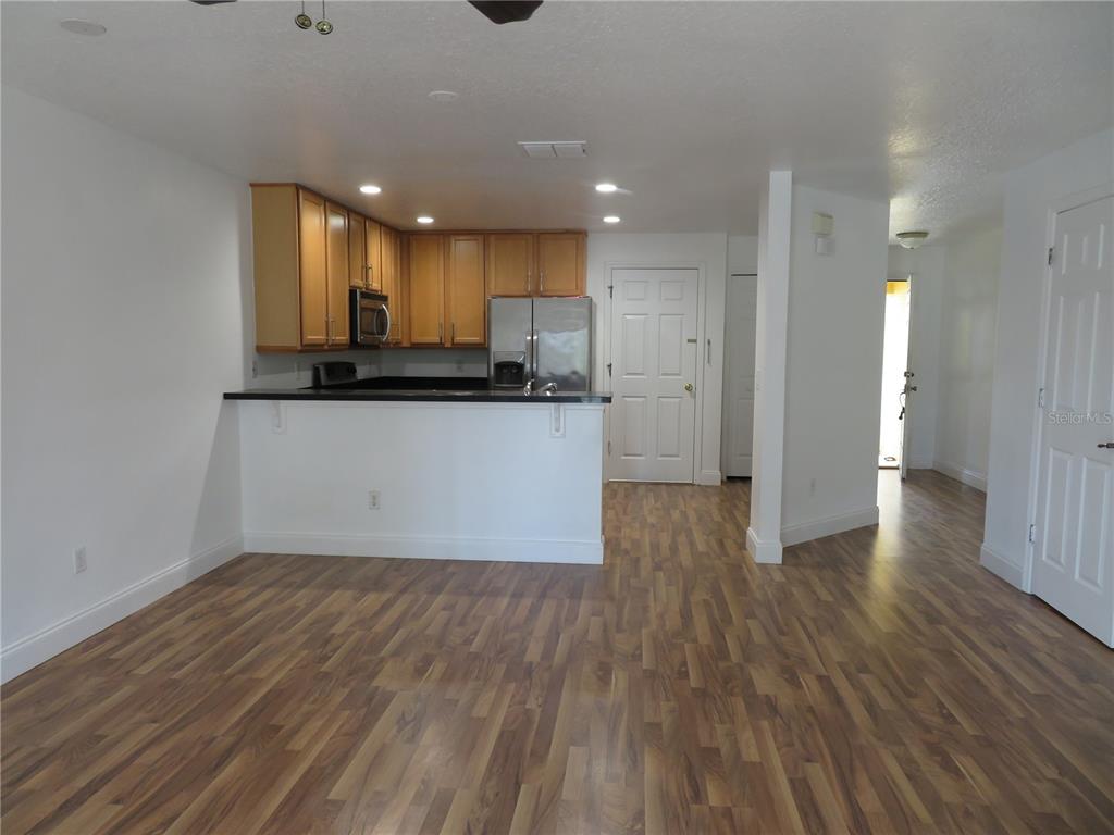 A kitchen with wood cabinets and stainless steel appliances overlooks an open living area — 3387 CARUSO PLACE, OVIEDO, FL