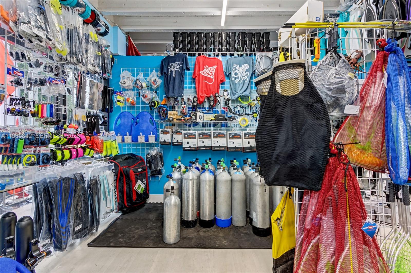 A retail store displays scuba diving equipment, including air tanks, fins, and various accessories — 24 NE 1st Ave, Dania Beach FL 33004, DANIA BEACH, FL
