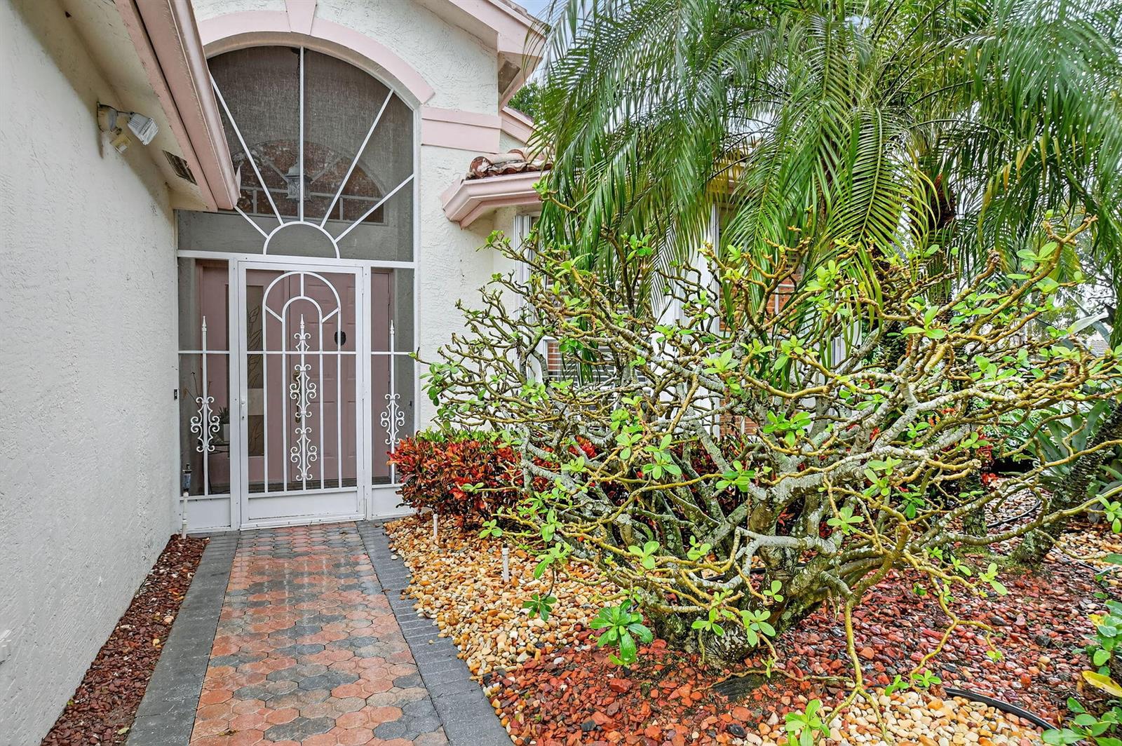 A paved walkway leads to a front door with a decorative white metal security gate — 6568 Malta Drive, Boynton Beach FL 33437, BOYNTON BEACH, FL