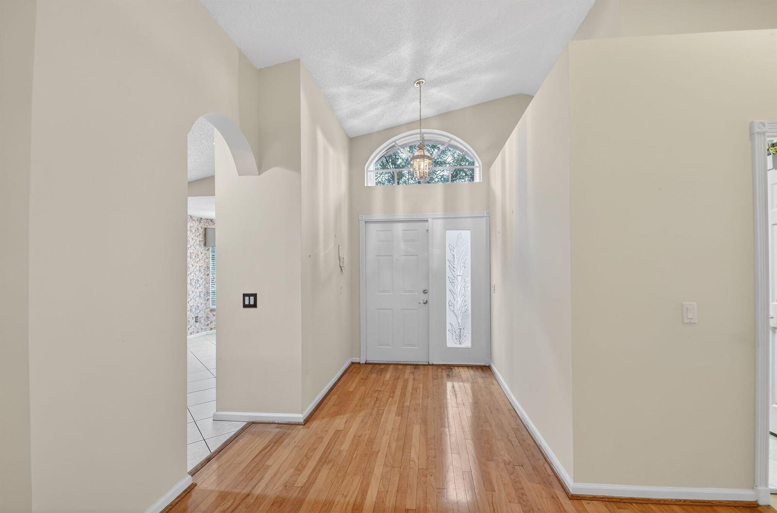 A foyer with hardwood floors, a vaulted ceiling, and a white front door with sidelight — 6568 Malta Drive, Boynton Beach FL 33437, BOYNTON BEACH, FL