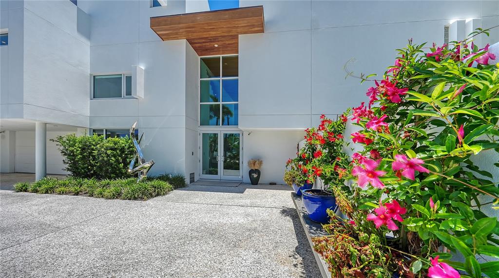 The exterior of a modern white house features a wooden entryway overhang and potted flowers — 246 MORNINGSIDE DRIVE, SARASOTA, FL