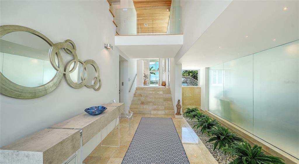 A modern entryway features a stone console table, a geometric mirror, and an indoor garden — 246 MORNINGSIDE DRIVE, SARASOTA, FL