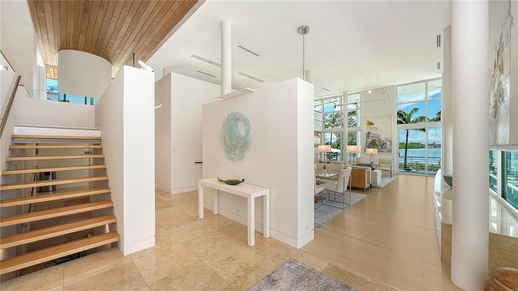 A bright, modern foyer features a floating wooden staircase, tile flooring, and a central partition — 246 MORNINGSIDE DRIVE, SARASOTA, FL