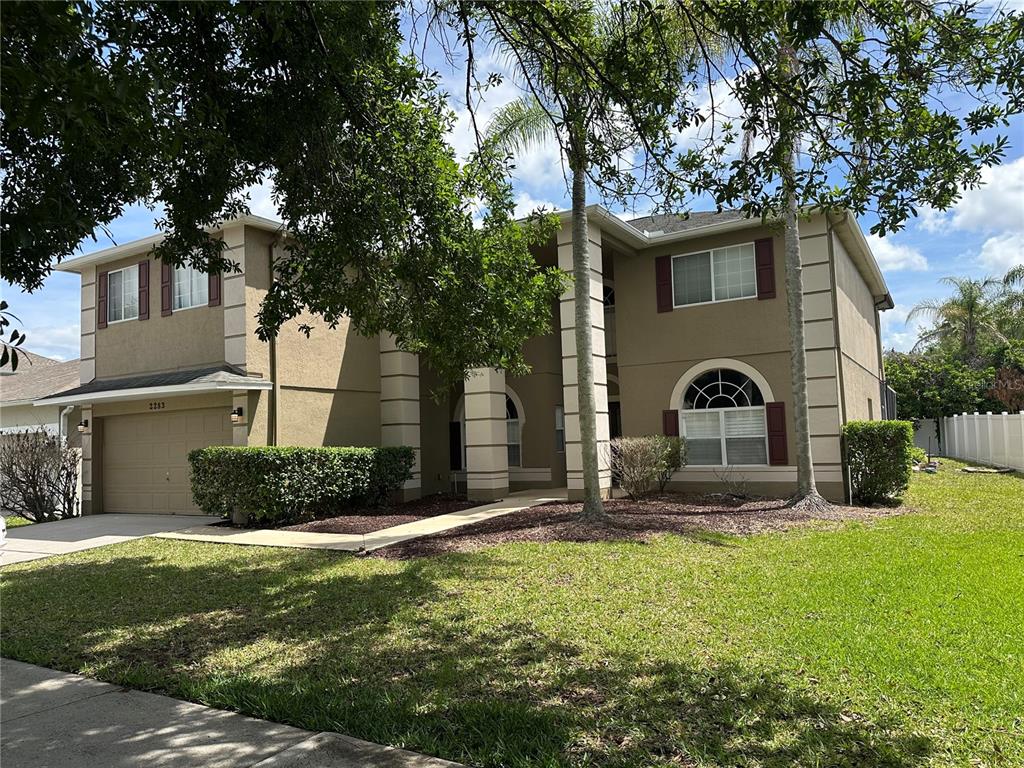 A two-story house with a tan stucco exterior, a garage, and a front lawn — 2283 STONE CROSS CIRCLE, ORLANDO, FL
