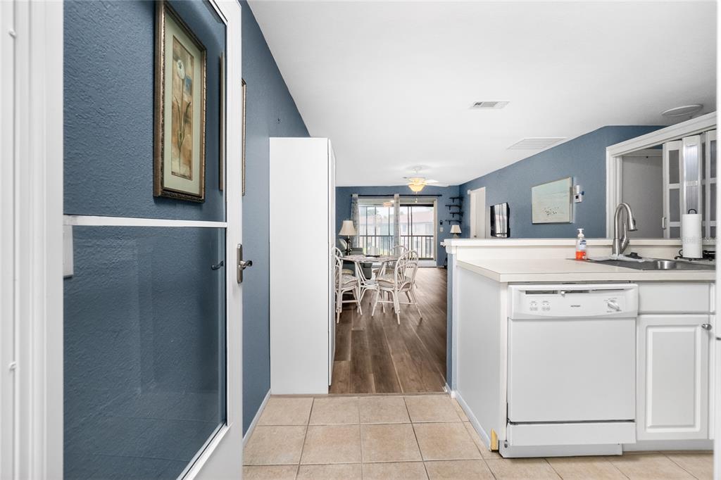 A view from a doorway looking into a kitchen with white appliances and a dining area — 25100 SANDHILL BOULEVARD UNIT G204, PUNTA GORDA, FL