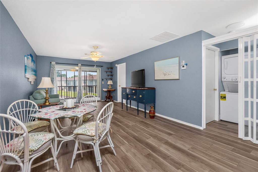 A dining area and living space with blue walls, wood-look flooring, and a laundry closet — 25100 SANDHILL BOULEVARD UNIT G204, PUNTA GORDA, FL