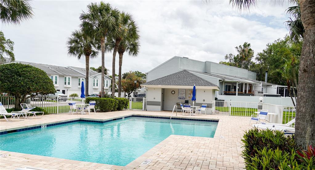 A swimming pool with a paved deck, palm trees, and a clubhouse building — 1963 GEORGIA CIRCLE N, CLEARWATER, FL