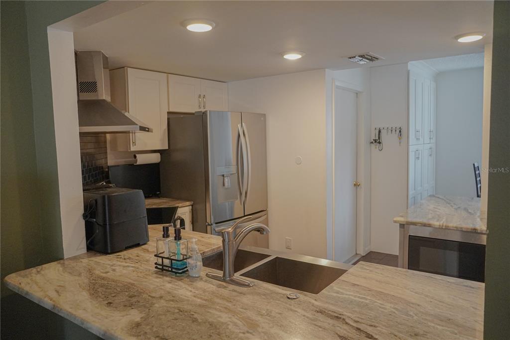 A kitchen features granite countertops, a stainless steel sink, and stainless steel appliances — 1963 GEORGIA CIRCLE N, CLEARWATER, FL