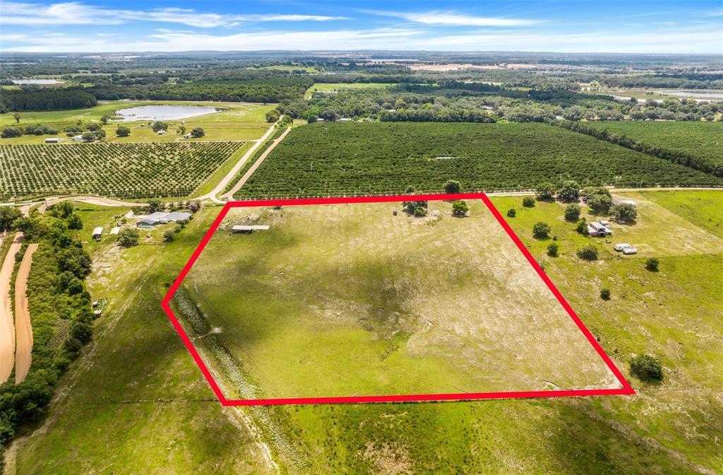 An aerial view shows a large, open grassy lot outlined in red near agricultural fields — SMITH ROAD, GROVELAND, FL