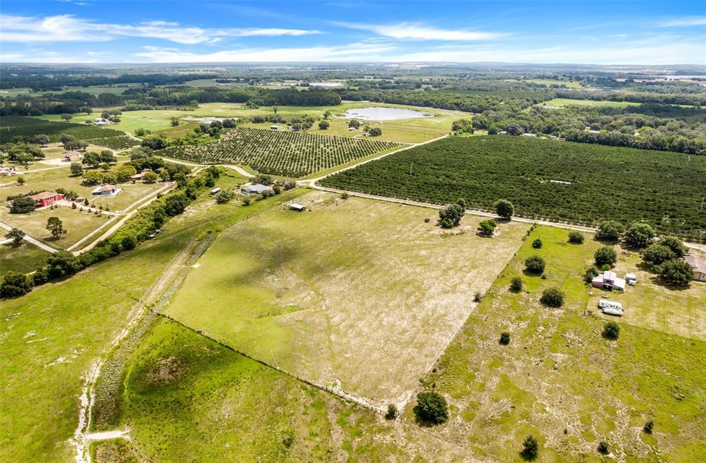 An aerial view shows a large, open grassy field bordered by orchards and rural properties — SMITH ROAD, GROVELAND, FL