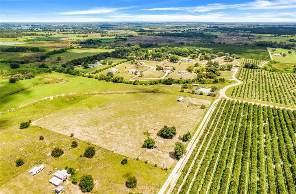 An aerial view shows a large grassy field, a small red building, and rows of trees — SMITH ROAD, GROVELAND, FL