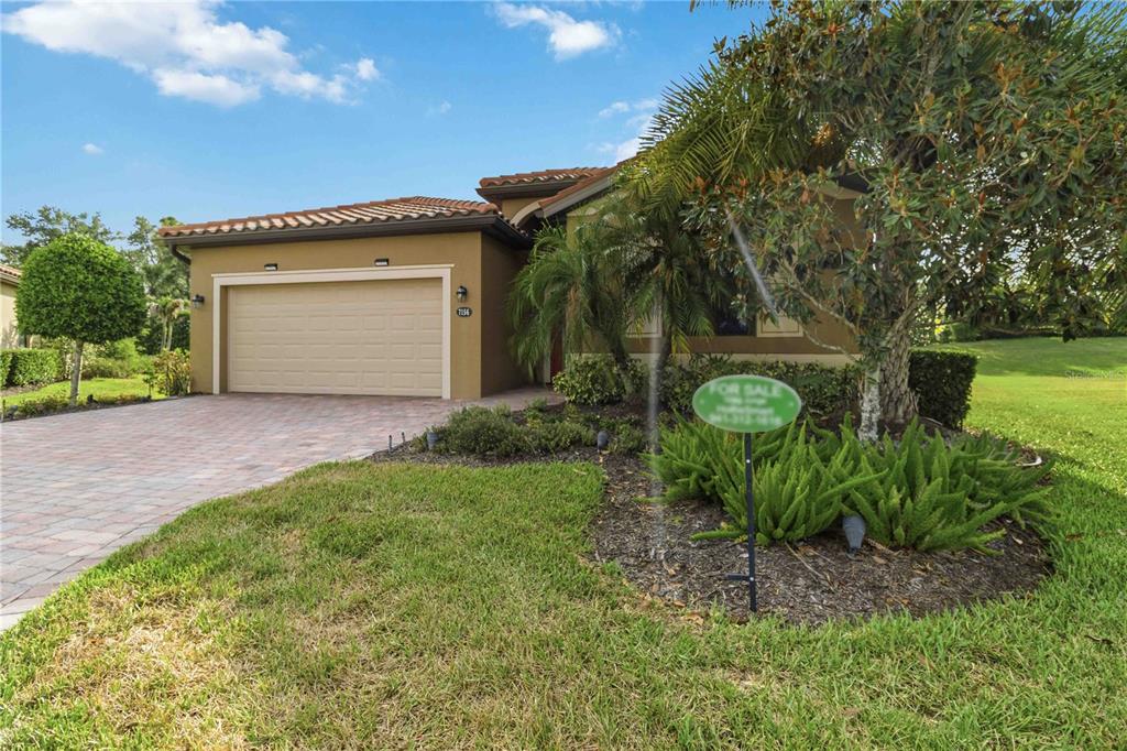 A single-story house with a tan stucco exterior, a two-car garage, and a landscaped front yard — 7156 MARSH VIEW TERRACE, BRADENTON, FL