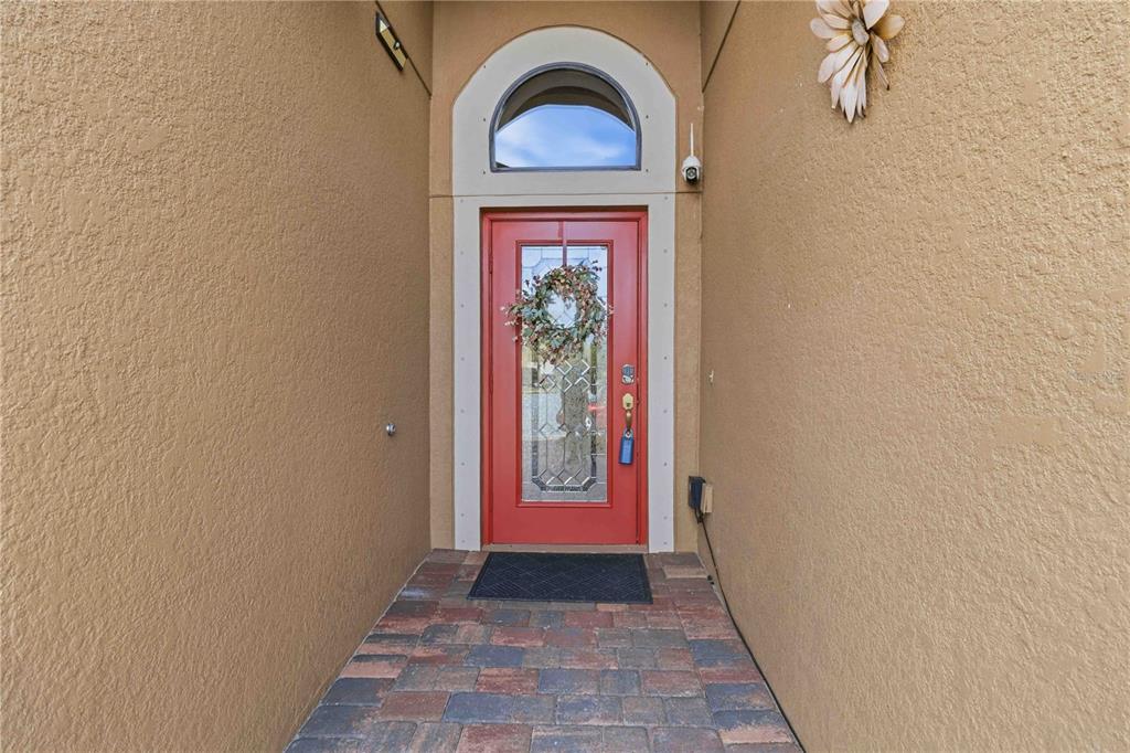A red front door with a glass insert and wreath sits under an arched transom — 7156 MARSH VIEW TERRACE, BRADENTON, FL