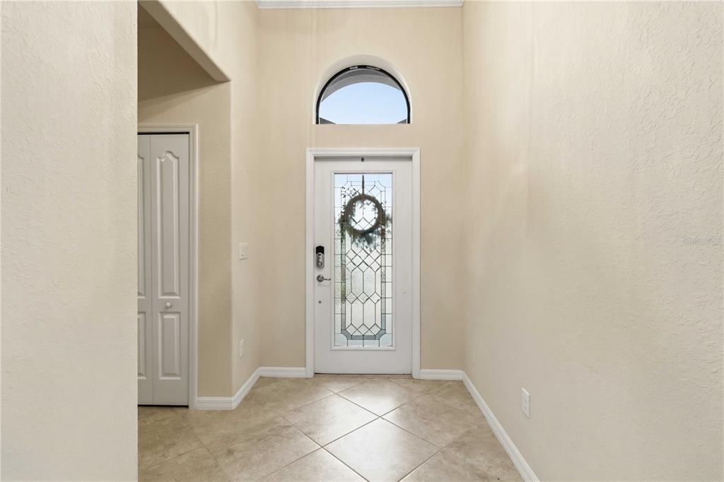 A foyer features beige tile flooring, a white front door with glass inserts, and a transom — 7156 MARSH VIEW TERRACE, BRADENTON, FL