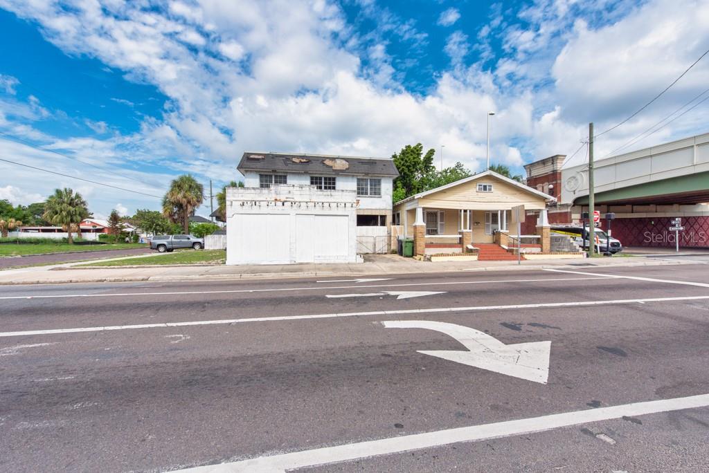 A two-story white building and a yellow bungalow sit beside a road under a sky — 1406 N HOWARD AVENUE, TAMPA, FL