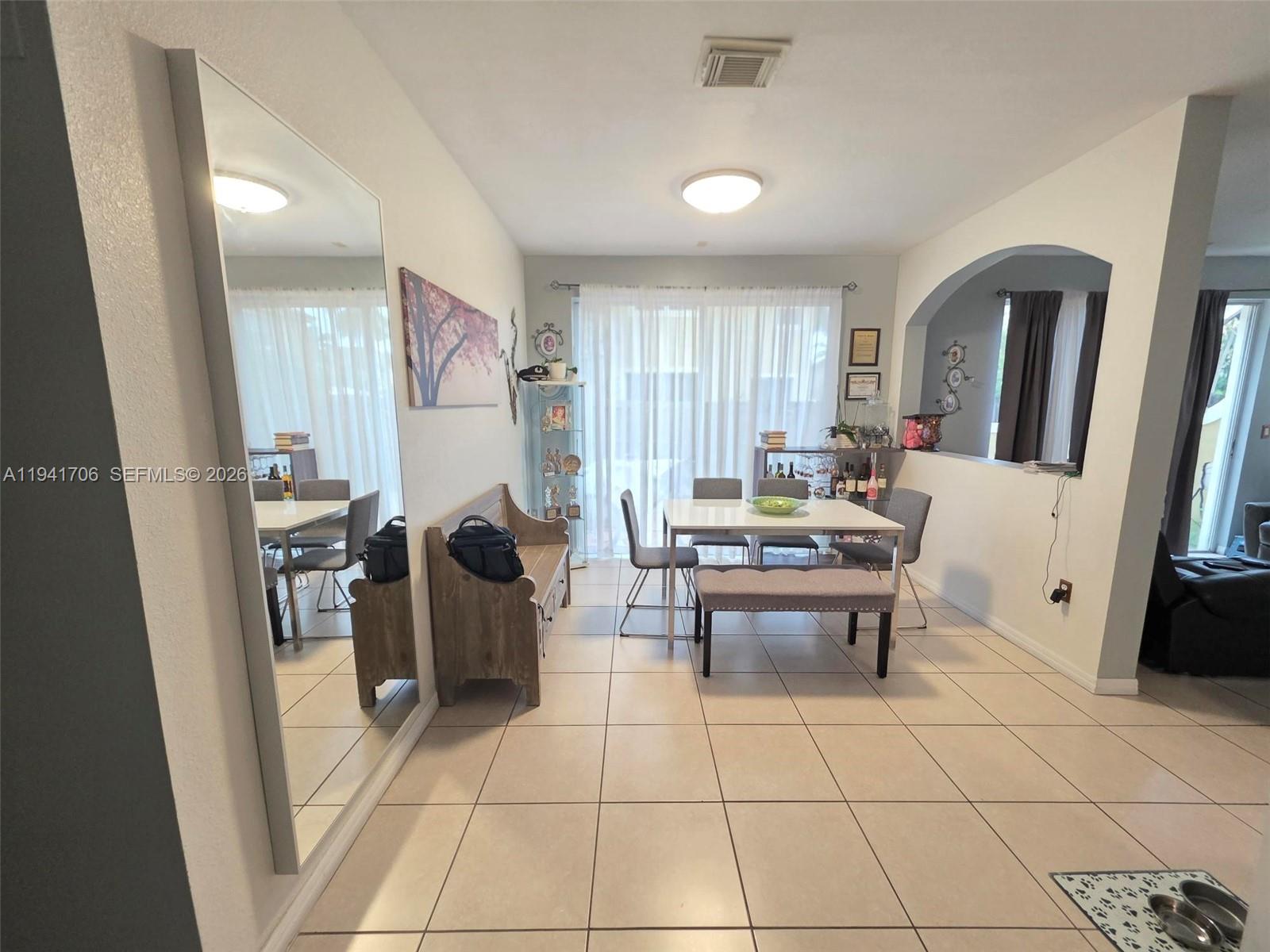A dining area features a white table, a bench, chairs, and a large wall mirror — 11702 SW 137th Pl, Miami FL 33186, MIAMI, FL