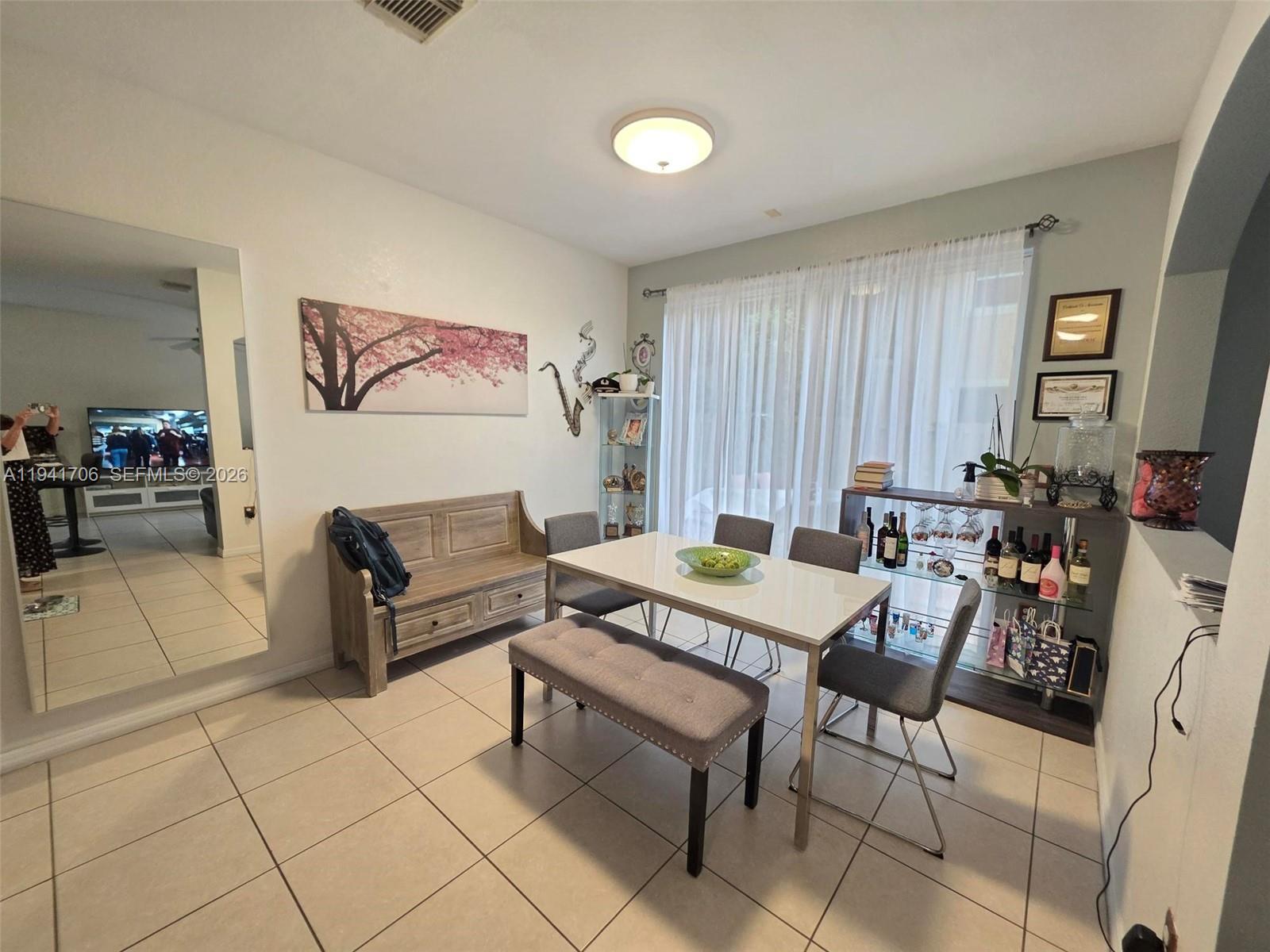A dining room features a white table, gray chairs, a bench, and a glass bar — 11702 SW 137th Pl, Miami FL 33186, MIAMI, FL