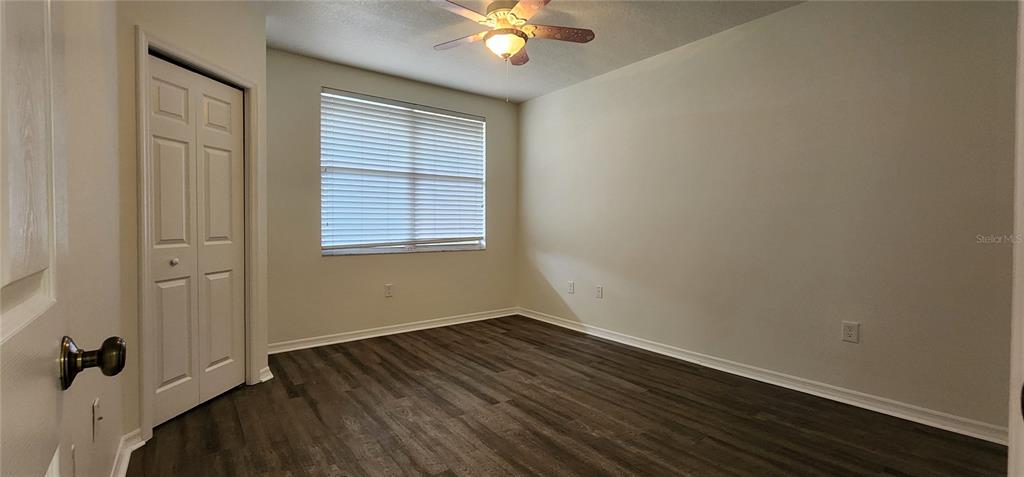An empty bedroom features wood-look flooring, a ceiling fan, and a white closet door — 960 STARKEY UNIT 3302, LARGO, FL