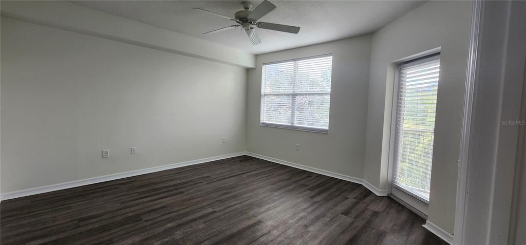 An empty bedroom features wood-look flooring, a ceiling fan, a window, and a glass door — 960 STARKEY UNIT 3302, LARGO, FL