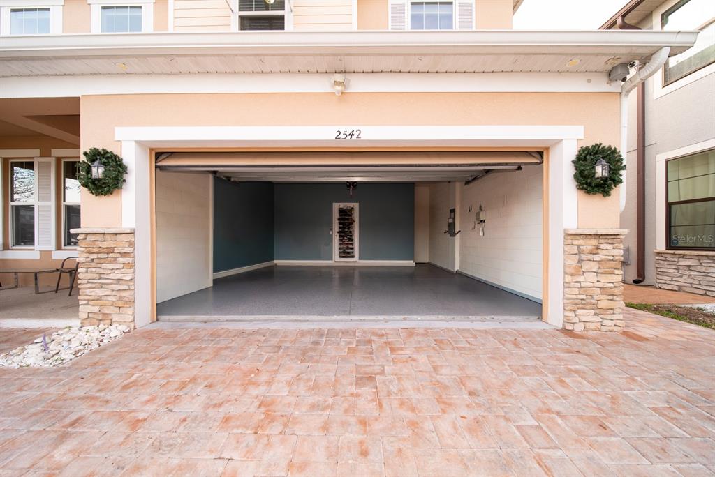 An open two-car garage with a gray floor and a blue accent wall — 2542 NOUVEAU WAY, KISSIMMEE, FL