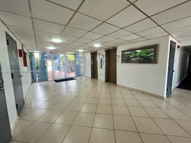 A tiled lobby features two elevator doors, a framed wall picture, and glass entry doors — 5050 NW 7th St # 220, Miami FL 33126, MIAMI, FL